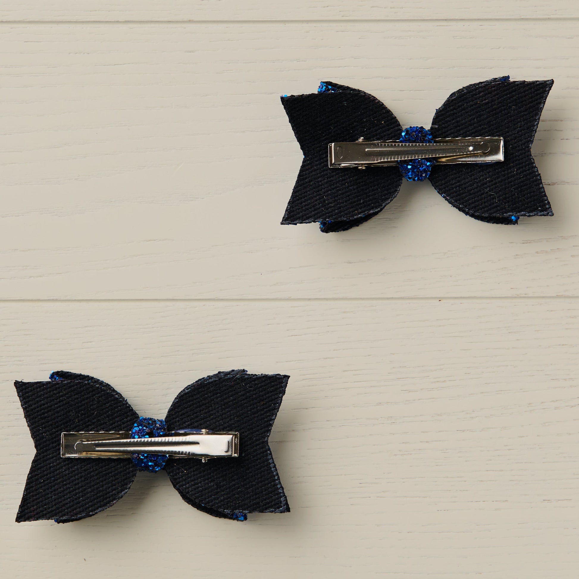 Photo showing the back of the hair bows with silver alligator clips on a light wooden surface