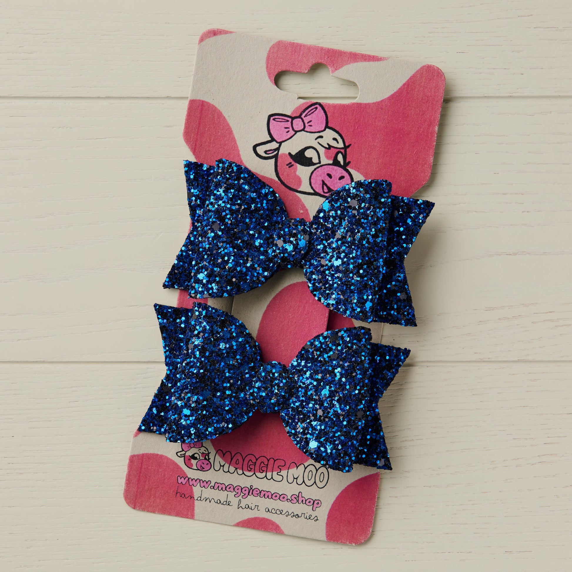 A pair of sparkly hair bows in Royal Blue on a display card