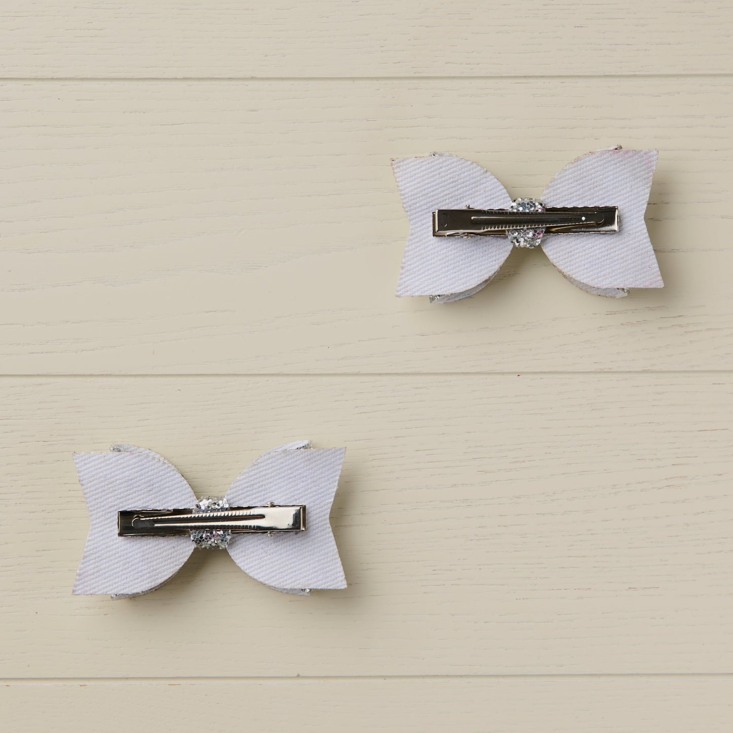 photo showing the back of the glitter bows with the alligator clips attached on a light wooden background