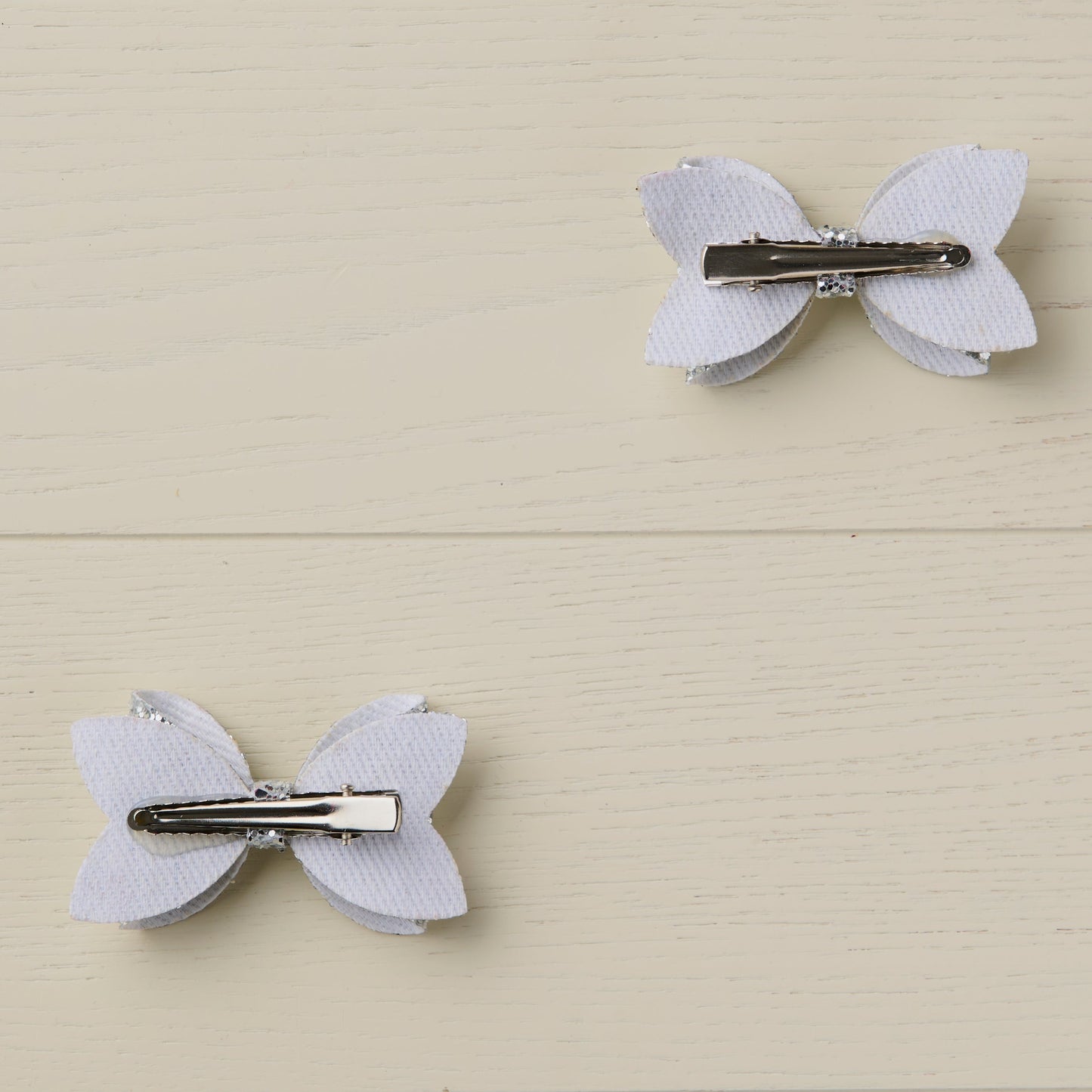 Photo showing the back of the hair bows with curved alligator clips clips on a light wooden surface