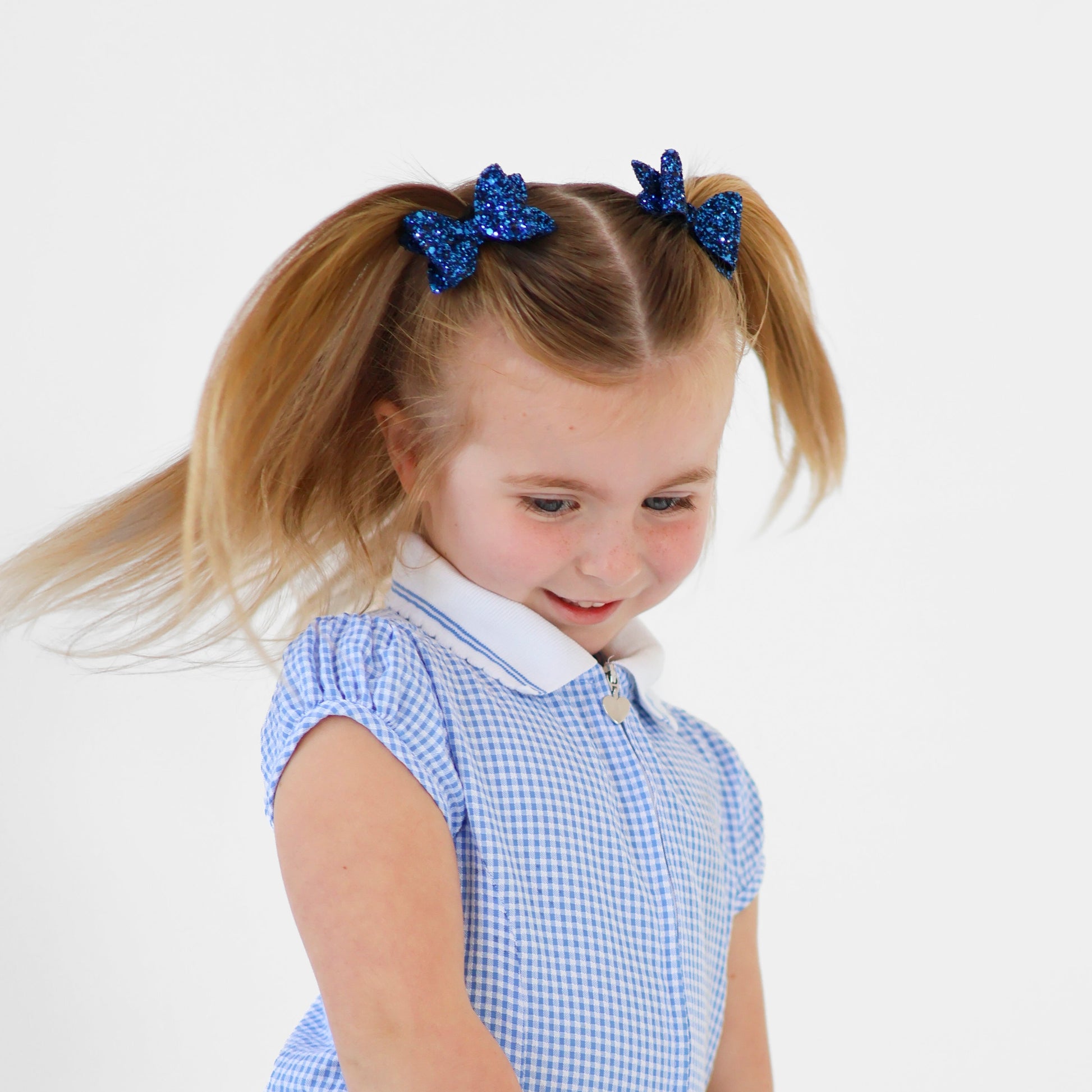 A girl twirling while wearing a school uniform and blue mini glitter bows