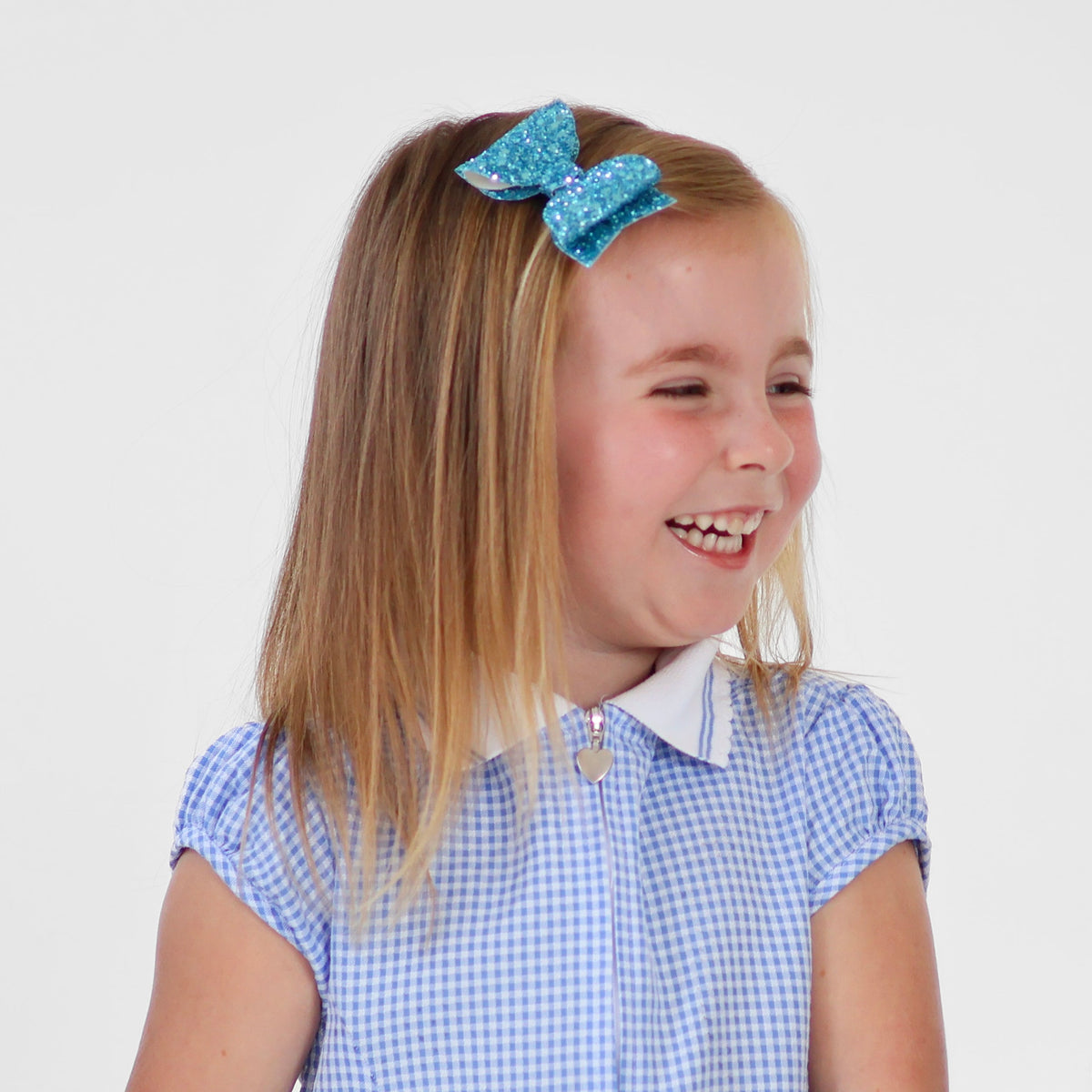 a happy girl wearing a sparkly blue hair bow with her school uniform