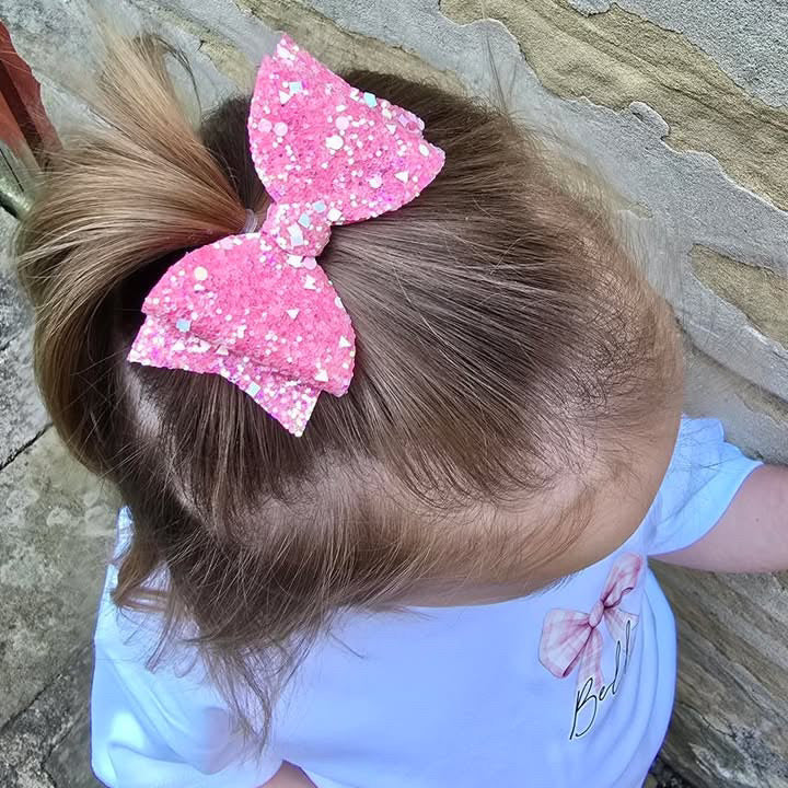 A girl with a pink glittery bow clipped to her ponytail.