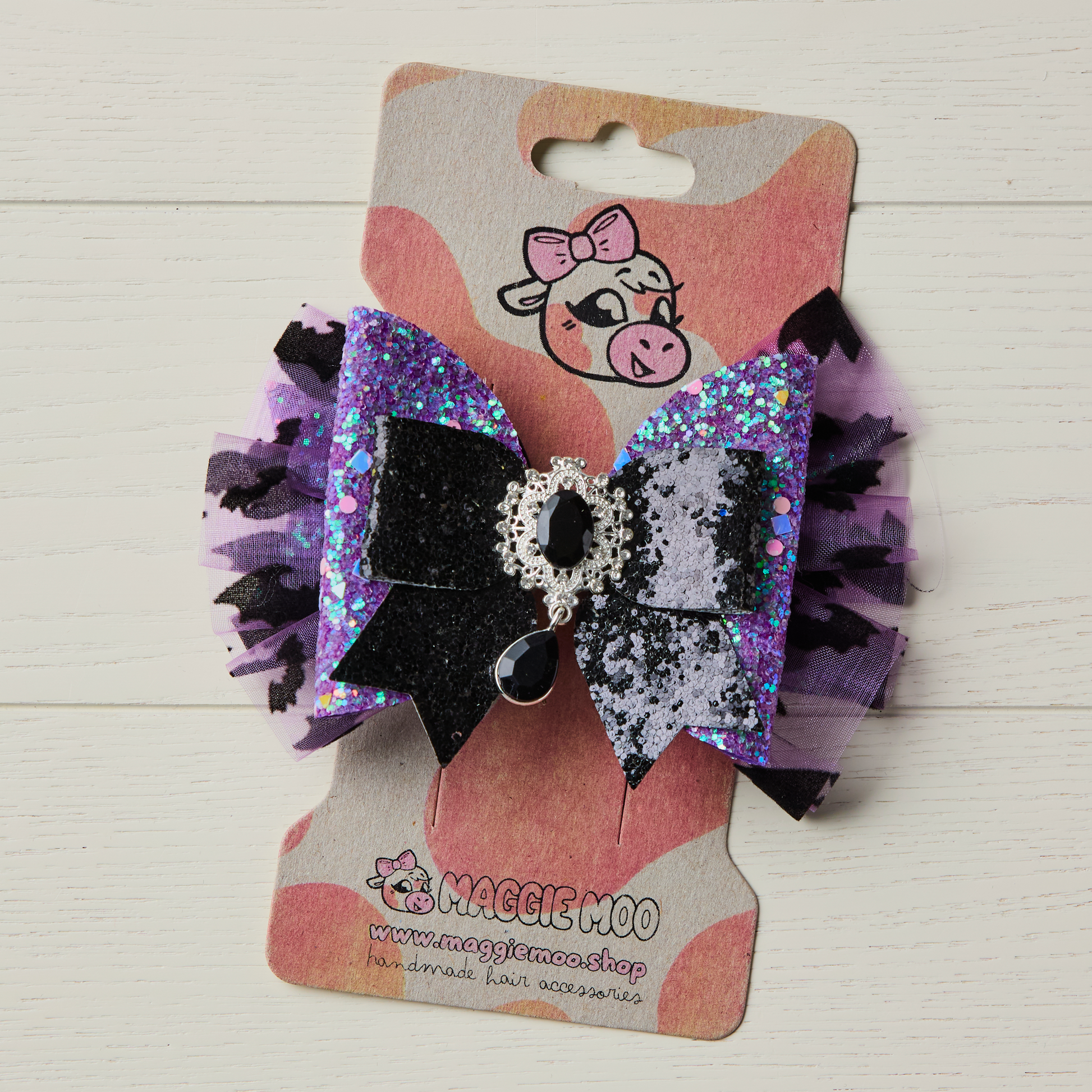 purple and black layered glitter bow on a display card
