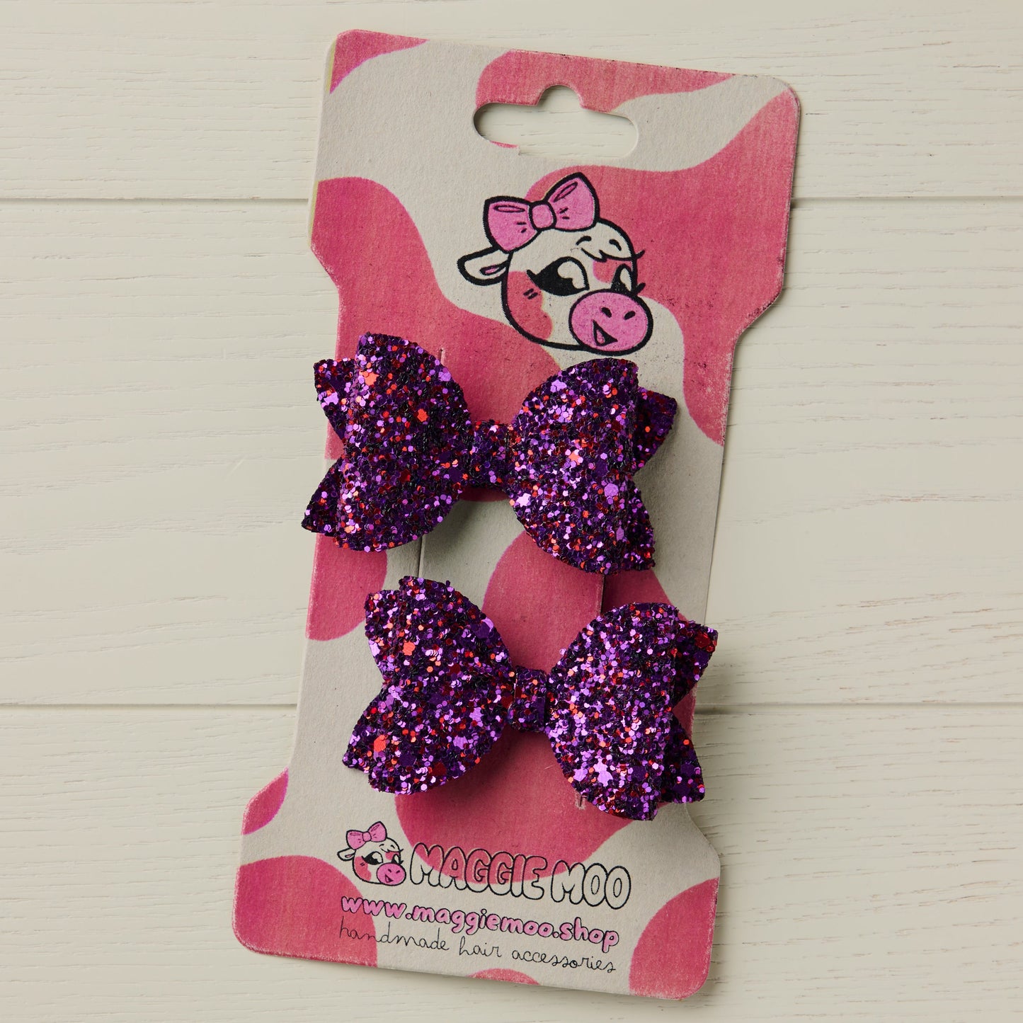 two small purple glitter bows on a display card