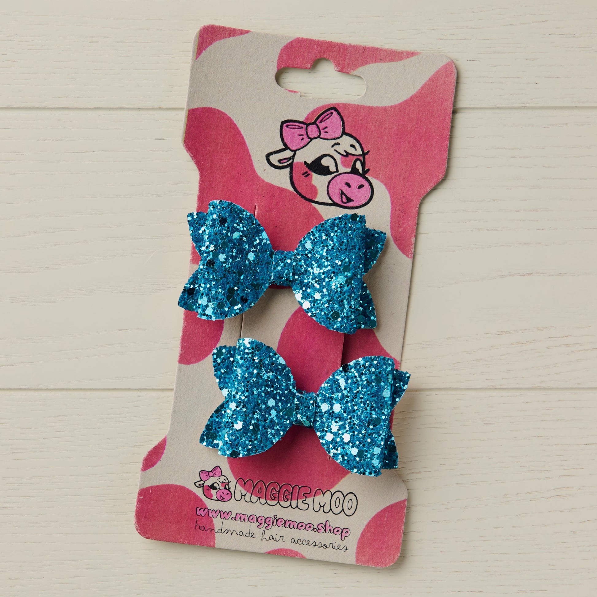 sparkly blue mini hair bows clipped onto a display card with a cute cow logo
