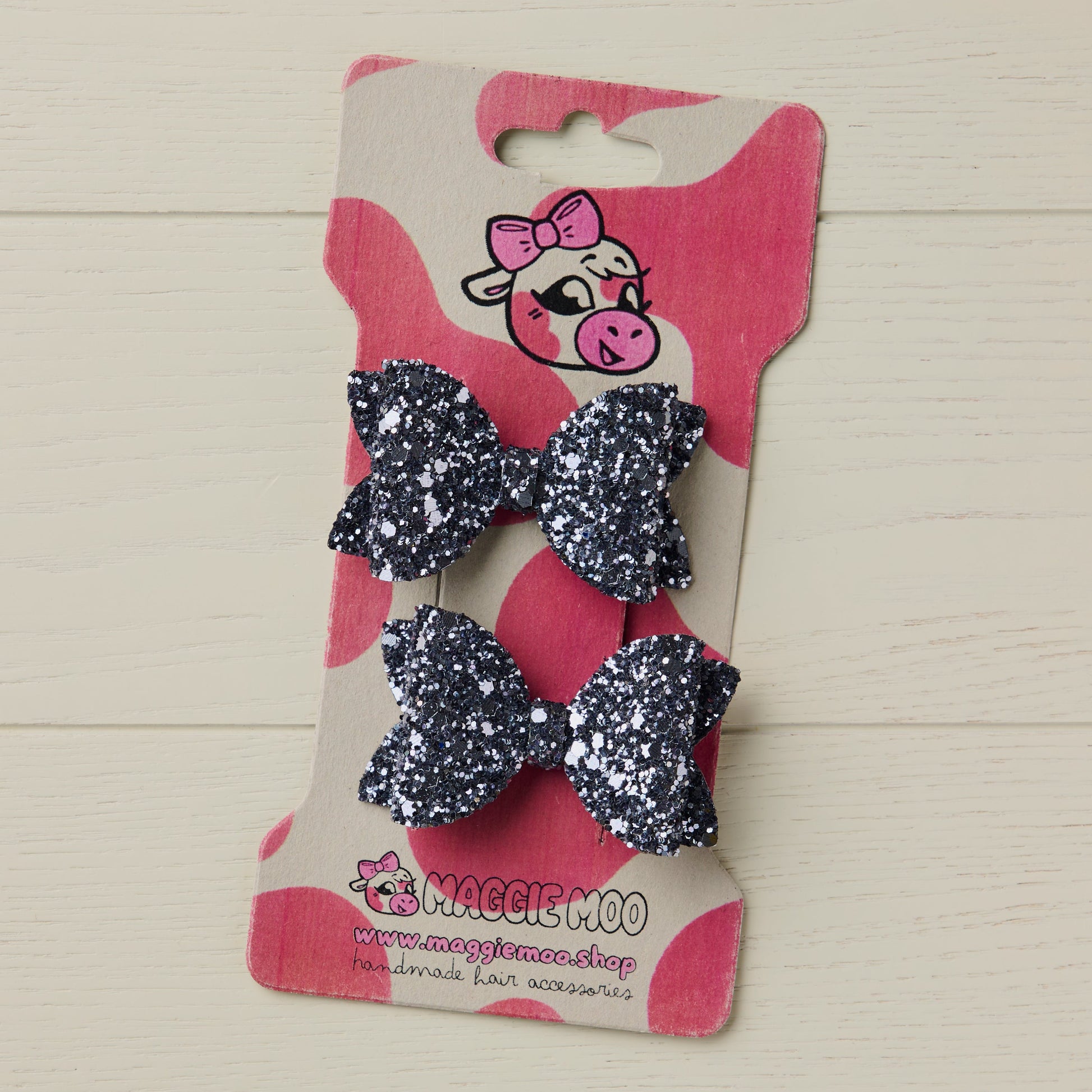 two dark grey glitter bows on a display card