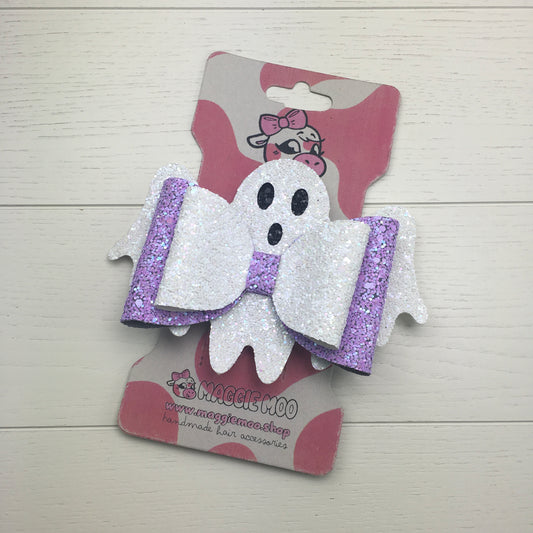A handmade large lilac and white confetti glitter Halloween hair bow on a recycled card display card with a cute cow logo.