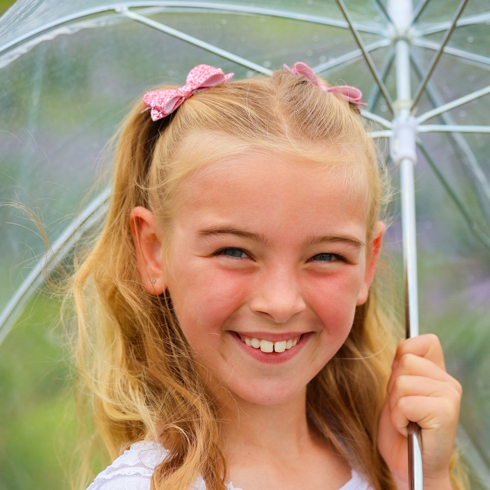 photo of a happy girl wearing two pink mini glitter bows