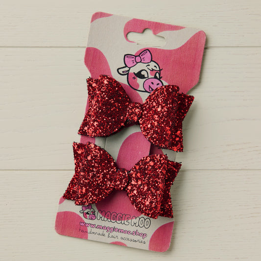 Two sparkly red glitter bows on a display card
