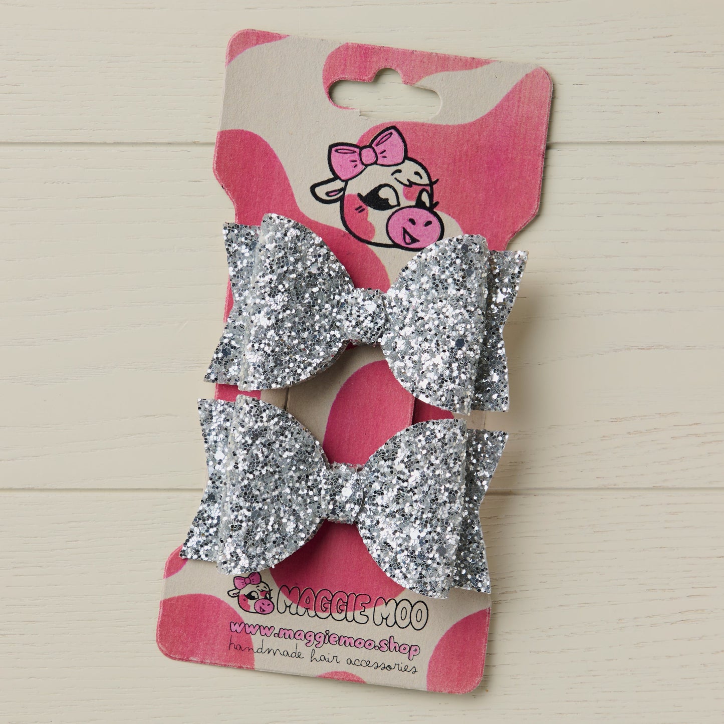 two sparkly silver hair bows on a display card