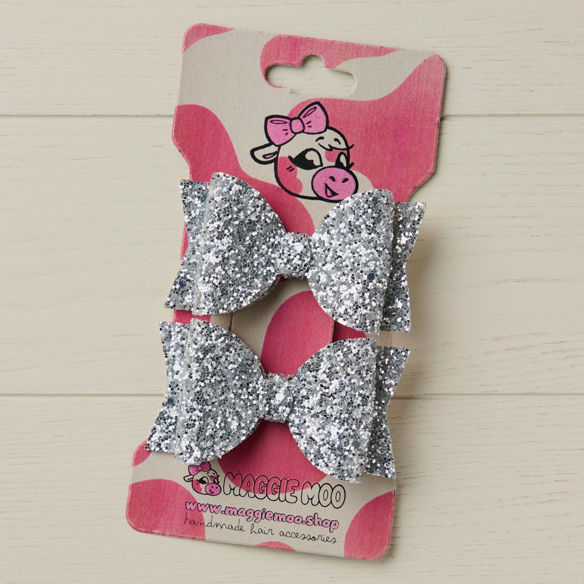 two sparkly silver hair bows on a display card