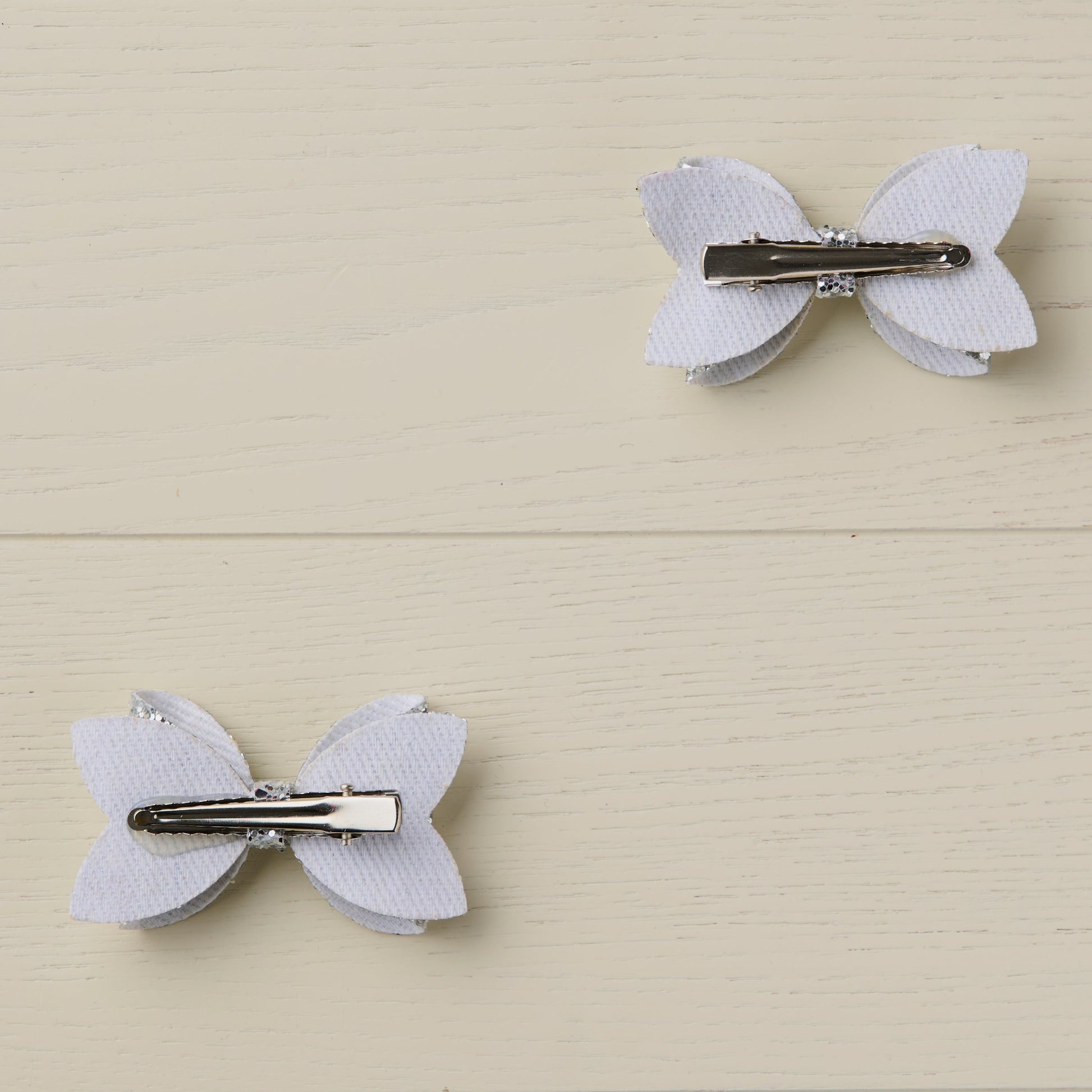 Photo showing the back of the hair bows with curved alligator clips clips on a light wooden surface