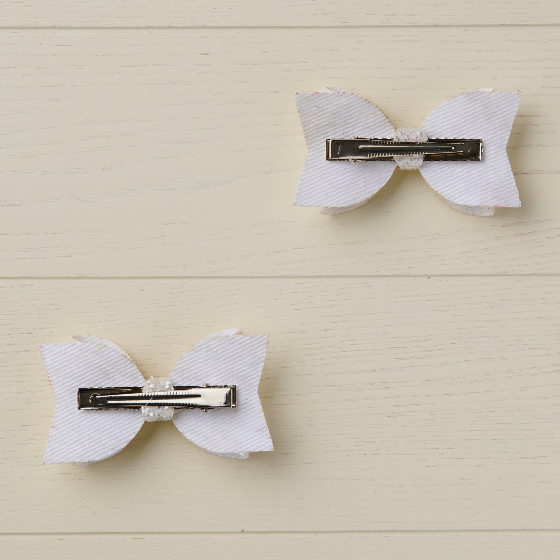photo showing the back of the bows with flat alligator clips on a light wooden surface